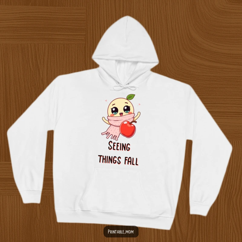 Funny hoodie depicting a knitted scarf with prominent googly eyes, waving goodbye to a falling apple in a humorous, animated scene.
